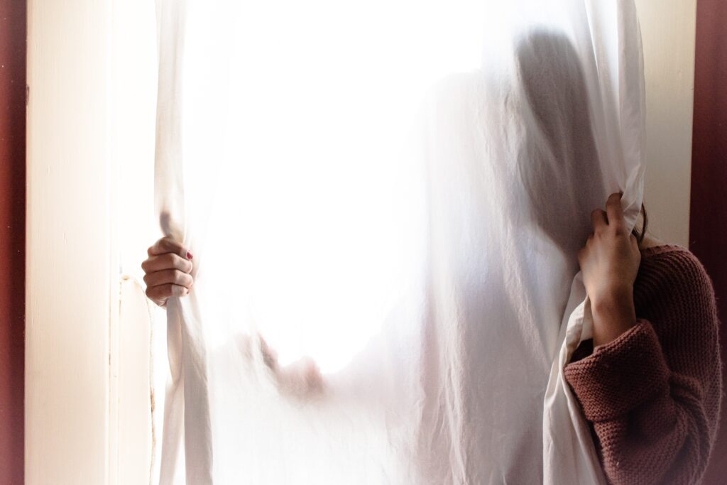 a person hiding behind the curtains in a window