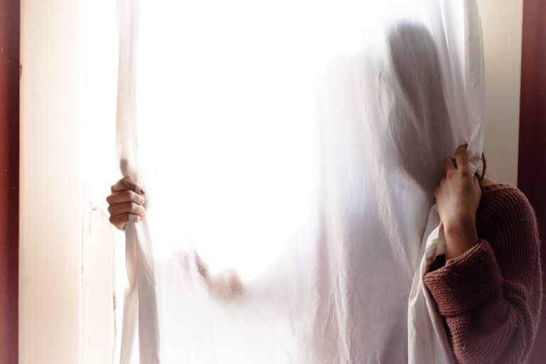 a person hiding behind the curtains in a window