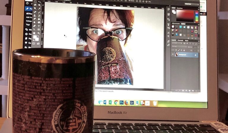 My college graduation mug with my name on it in front of a laptop with a photo of me drinking from that mug on the screen.
