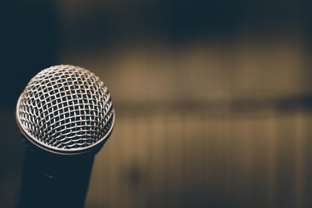 A microphone is left of the image with open space blurred to the right.
